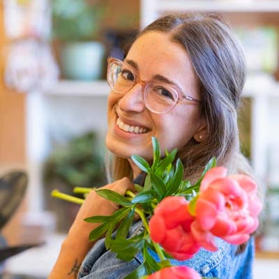 Portrait of Amy Giarratana, holding flowers over her shoulder.